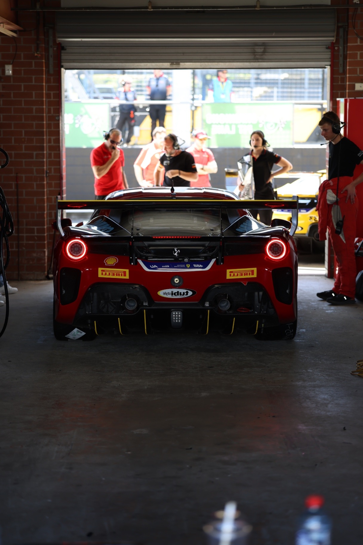 Red Ferrari 488 with glowing tail lights parked in the garage